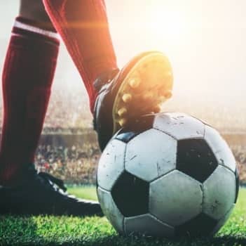 Zdjęcie w zbliżeniu nogi piłkarza opierającej się o piłkę - tak jak by zaczynał grę.